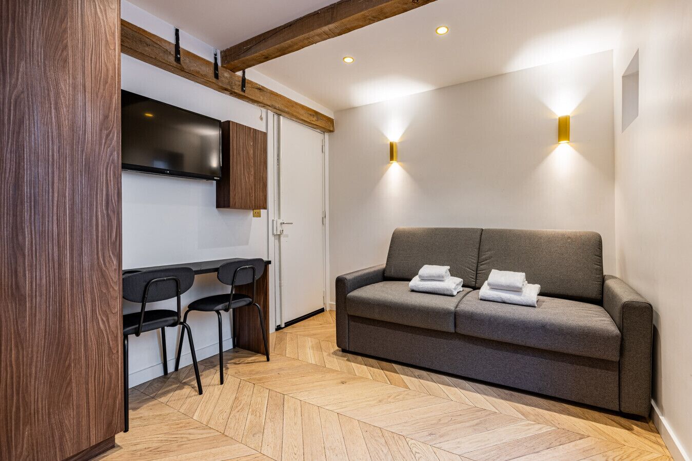 Une pièce moderne avec un canapé, deux fauteuils, un téléviseur et un plancher en bois.