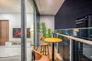 Un intérieur moderne avec une cloison en verre, un banc en bois, deux chaises, une petite table ronde et une plante en pot.