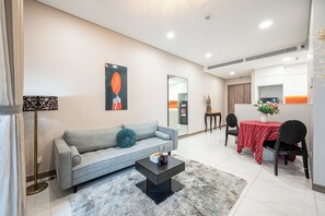 Un salon moderne avec un canapé gris, une table basse noire et un coin repas avec une nappe rouge.