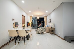 A modern living room with a dining area, a sofa, a TV, and a view of the city at night. - SUNWAH PEARL Premier Residence By An Gia Hospitality (Ho Chi Minh City)