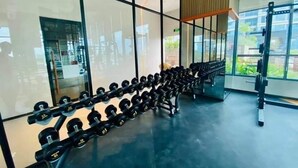 Ein Fitnessraum mit Reihen von Kurzhanteln auf Stativen und einer Gewichtheckbank.