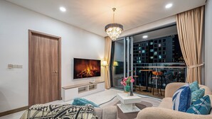 Ein modernes Wohnzimmer mit einem Flachbildfernseher, einer Kristallleuchtre, einem Sofa und einem großen Fenster mit Vorhängen.