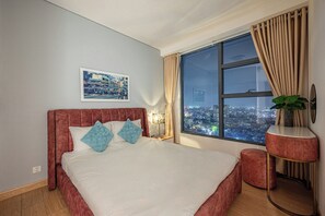 Une chambre d’hôtel avec un grand lit, une table de chevet, un miroir, une fenêtre donnant sur la ville et une plante.
