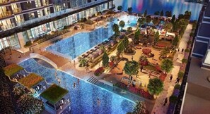 Een modern binnenzwembad met verschillende zones, omgeven door aangelegde tuinen en wandelpaden.