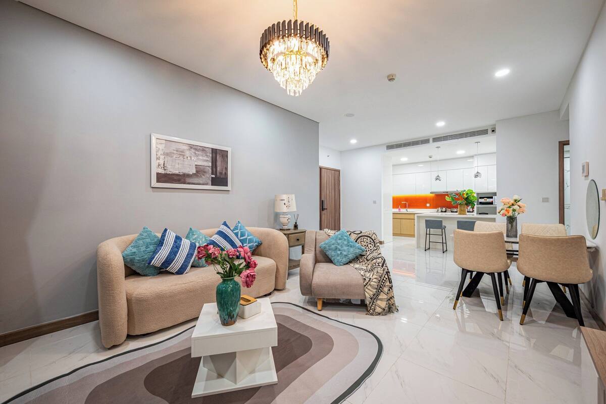 Un salon moderne avec un canapé beige, une table basse et un lustre.