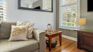 Una sala de estar con sofá, una mesita de madera, una lámpara y una ventana con persianas.