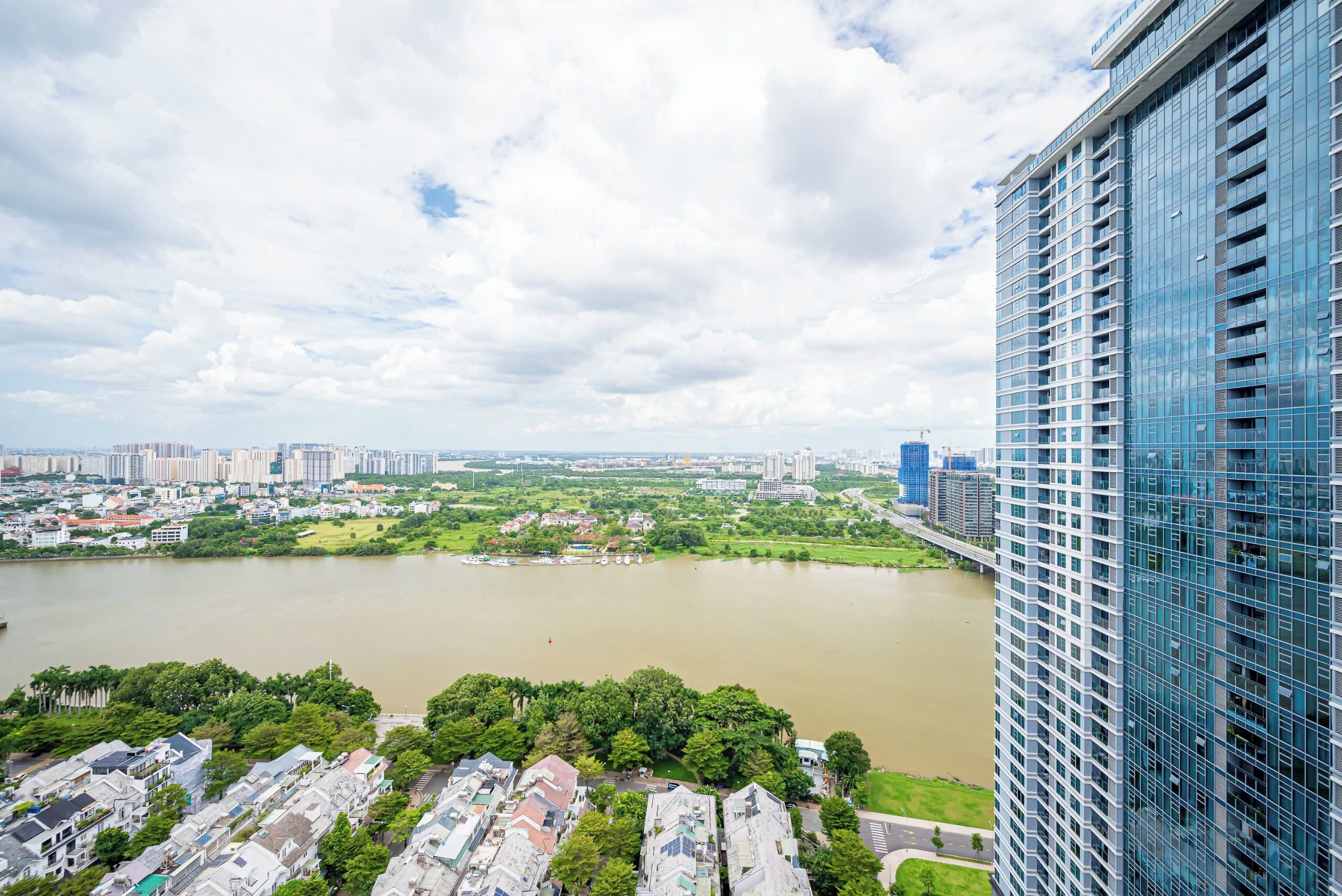 A high-rise building with a view of a river and surrounding greenery.