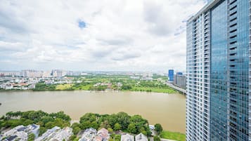 A high-rise building with a view of a river and surrounding greenery.