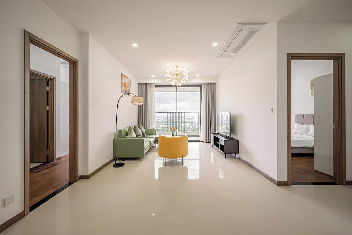 Un salón amplio con sofá, un sillón amarillo, televisión y un balcón con vistas.