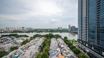 A high-rise building with a modern glass facade overlooking a river and a densely packed residential area with traditional-style houses.