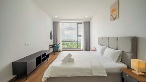 A modern hotel room with a large bed, a desk, a chair, and a view of the city through a large window. - OPAL SAIGON PEARL Premier Residence (Ho Chi Minh City)