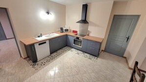 A compact kitchen with a microwave, stove, sink, and a small countertop. - L'Étoile Normande - Country house (Bourgnac)