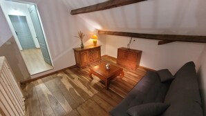 A living room with wooden flooring, a dark grey sofa, a wooden coffee table, and two wooden cabinets. - L'Étoile Normande - Country house (Bourgnac)