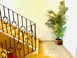 Una escalera con barandales negros ornamentados y una planta en maceta a su lado.