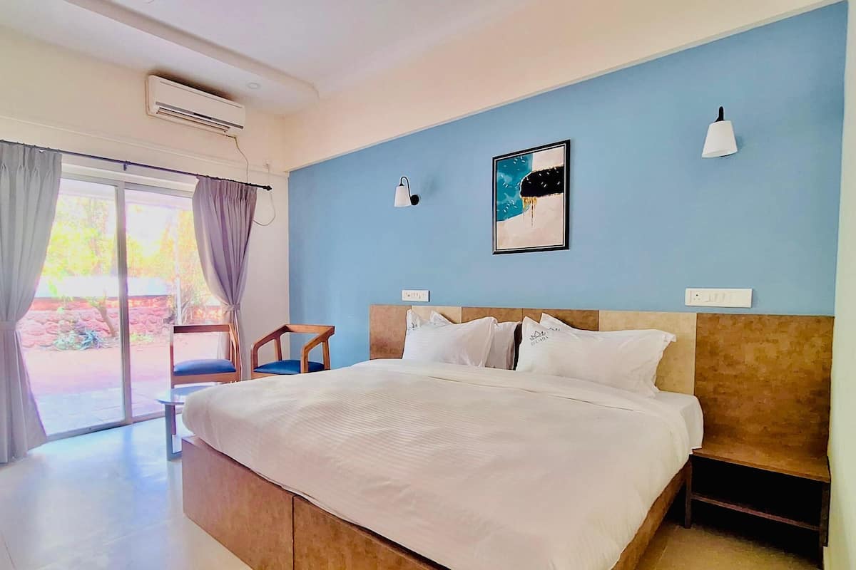 Una camera d'albergo con un letto, una scrivania con un bollitore, una sedia e vista sull'esterno.
