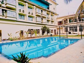 Una piscina rodeada por un edificio con varios balcones y unidades de aire acondicionado.