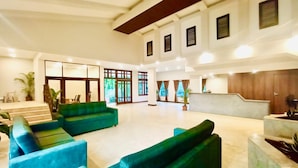A spacious lobby with a high ceiling, large windows, and a reception desk. - The Regalia Goa (Alto de Porvorim)