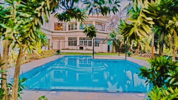 A swimming pool with a clear view of a building in the background. - The Regalia Goa (Alto de Porvorim)