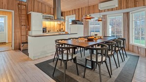 A modern kitchen with wooden paneling, a central island, and pendant lighting.