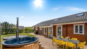 A wooden house with a patio, a hot tub, and yellow chairs.