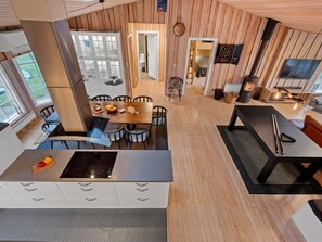 Une cuisine moderne dotée d’un îlot central, de murs en bois et d’un coin repas avec une table et des chaises.