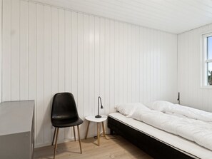 Ein Schlafzimmer mit einem Bett, einem Sessel, einem kleinen Tisch und einem Fenster.