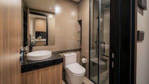A modern bathroom with a sink, toilet, and glass shower enclosure. - DE LA SOL Premier Residence (Ho Chi Minh City)