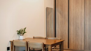 A conference room with a wooden table and chairs, a potted plant, and a sliding door in the background. - DE LA SOL Premier Residence (Ho Chi Minh City)