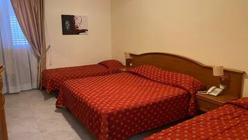 A hotel room with two beds, a bedside table with a lamp, and a painting on the wall.