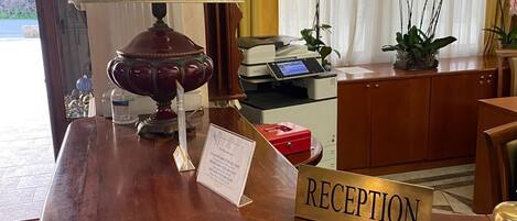Una mesa de recepción con un emblema de estrella, una lámpara, una impresora y un letrero que dice "RECEPTION".