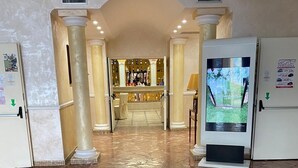 A lobby with a central circular mosaic floor design, a reception desk, and a refrigerator with a price list.