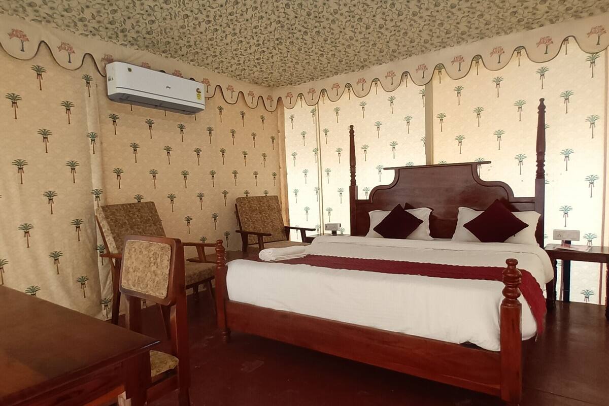 Une chambre à coucher avec un lit à baldaquin, une table en bois, deux chaises et un climatiseur au plafond.