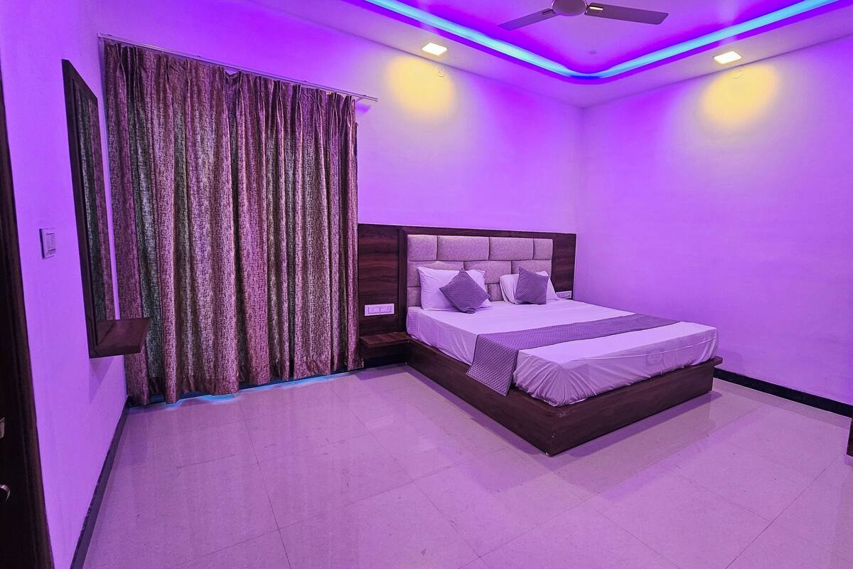 Une chambre à coucher avec un lit, des rideaux, un ventilateur de plafond et une armoire.