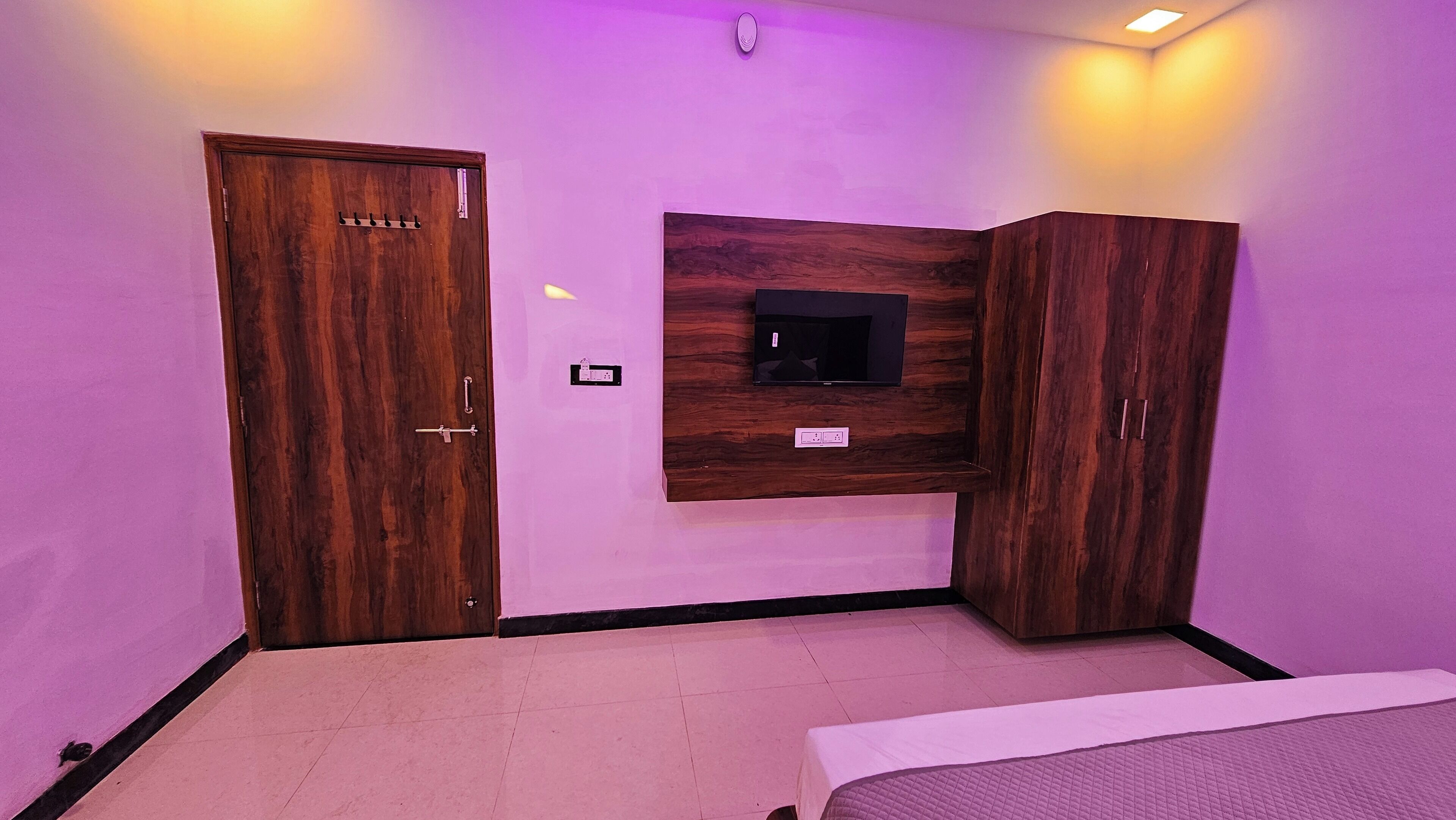 A bedroom with a bed, a wardrobe, and a TV mounted on the wall.