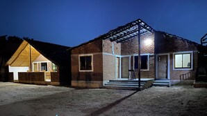 Een gebouw van baksteen met twee verdiepingen, een overdekte veranda en een klein bijgebouw.