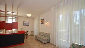 A living room with a sofa, a dining table, and a red counter. - Welcoming flat for a comfortable stay in Bibione (Bibione Pineda)