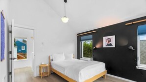 A bedroom with a bed, a small side table, a window, and a door leading to another room. - Ember & Glow Loft Retreat (Seattle)