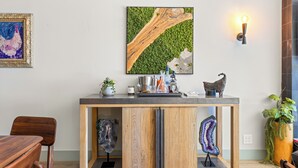 A wooden cabinet with a glass front, a framed painting, and a wall-mounted light fixture.