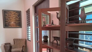 A room with a wooden shelf, a chair, a large vase, and a painting on the wall. - Enjoy Beverly Hills, Kingston, Jamaica, 4 bdrms, AC, WiFi, Spacious, Quiet, Safe (Kingston)