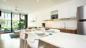 A modern kitchen with white cabinetry, a stainless steel refrigerator, and a dining area with white chairs and a table set for four. - Lovely One Bedroom With Amazing Terrace View!! (Playa del Carmen)