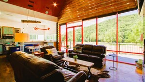 Ein geräumiger Wohnbereich mit großem Fenster zum Wald, eine Küche mit modernen Geräten und eine gemütliche Sitzecke.