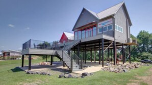 Ein zweistöckiges Haus mit einer überdachten Terrasse und einer Treppe, die zum oberen Stock führt.