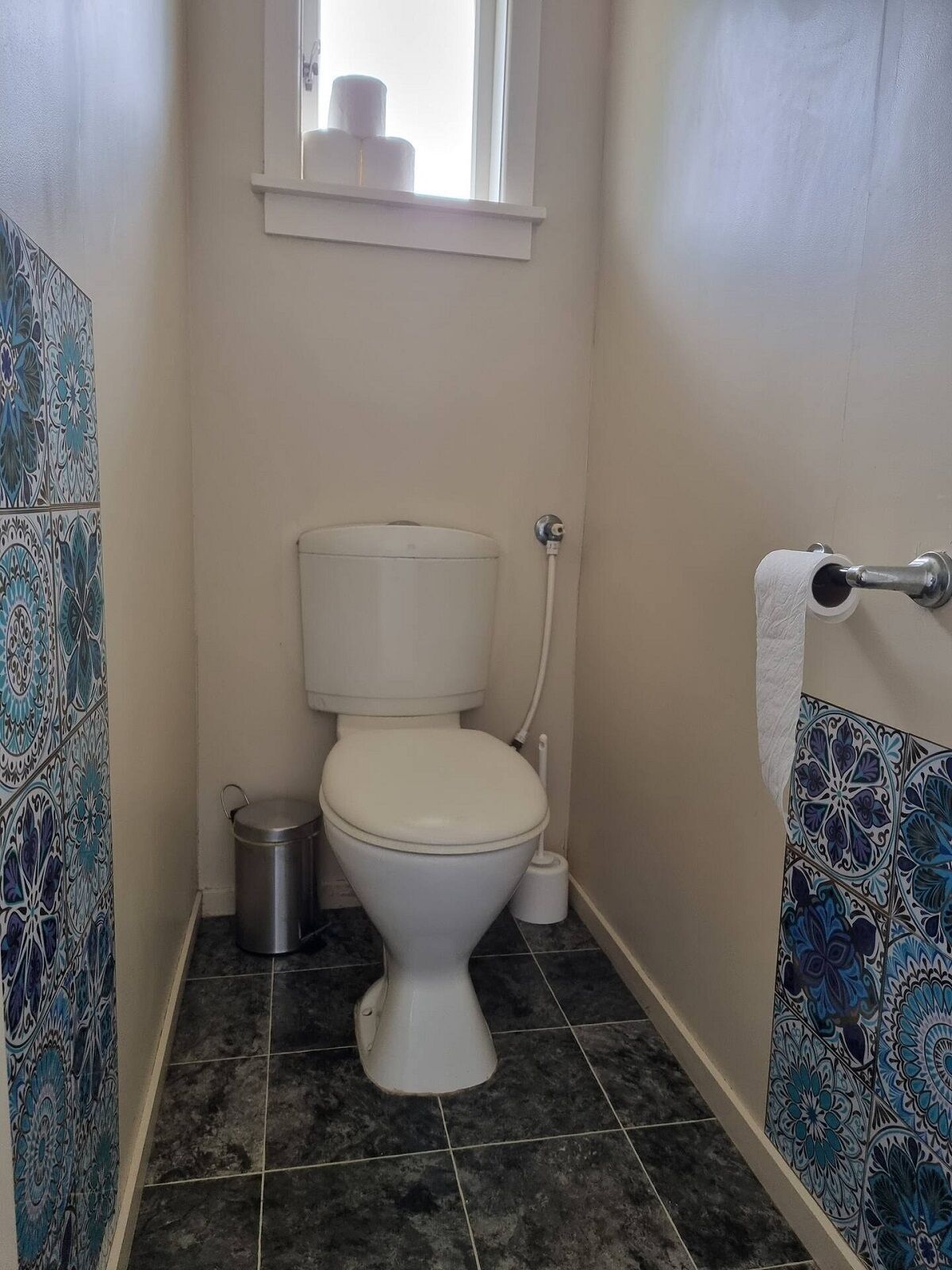 A small bathroom with a toilet, a bidet, and a trash can.