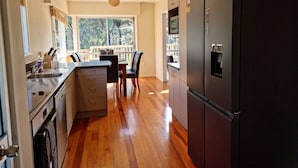 Una cocina moderna con piso de madera, comedor y un refrigerador grande.