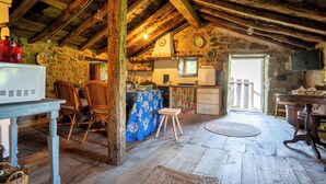 A rustic kitchen with stone walls, wooden beams, and a wooden table with chairs. - Cosy cottage in Los Valles Pasiegos, Cantabria: Lo Lucas 1920 (San Roque de Riomiera)