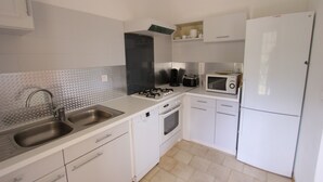 Una cocina compacta con lavamanos, estufa, microondas y refrigerador.