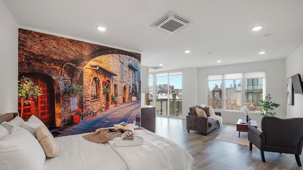 Une chambre d’hôtel moderne dotée d’un grand lit, d’un canapé et d’un balcon offrant une vue sur la ville.