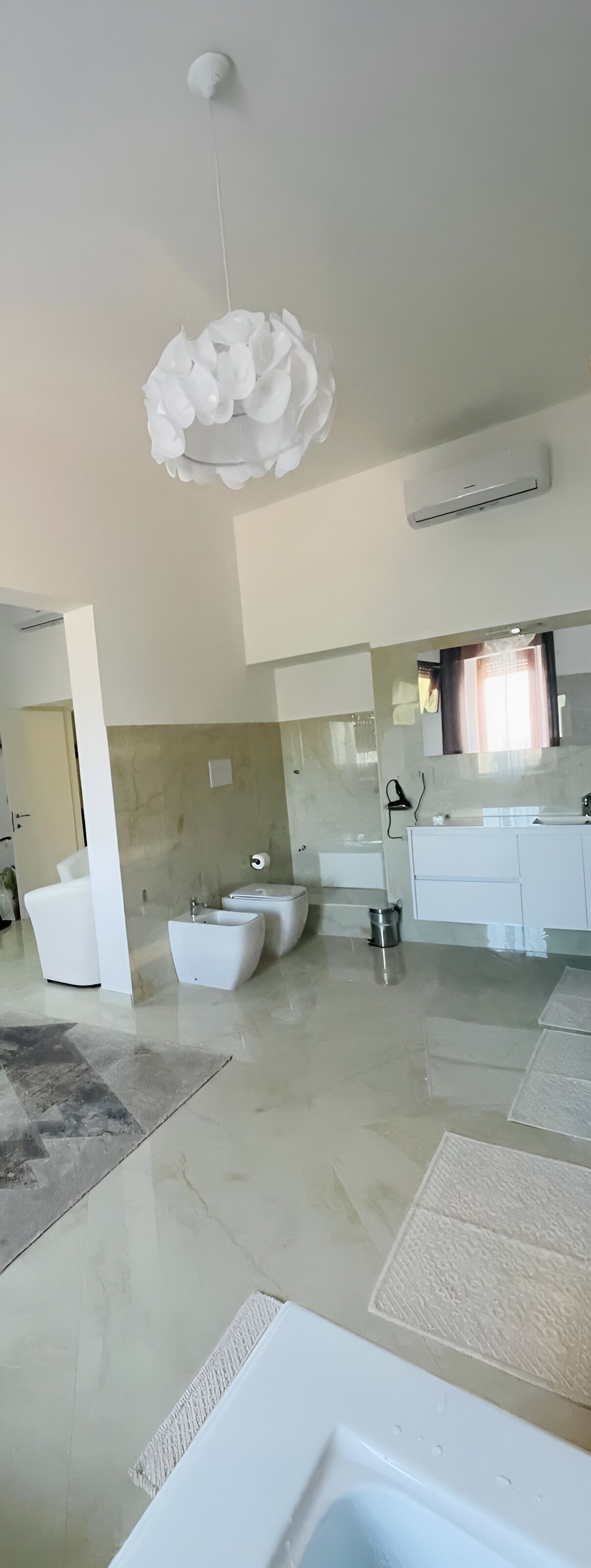 A modern bathroom with a large mirror, a white sink, and a bathtub.