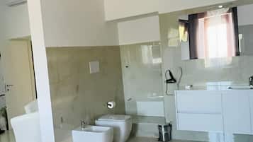 A modern bathroom with a large mirror, a white sink, and a bathtub.