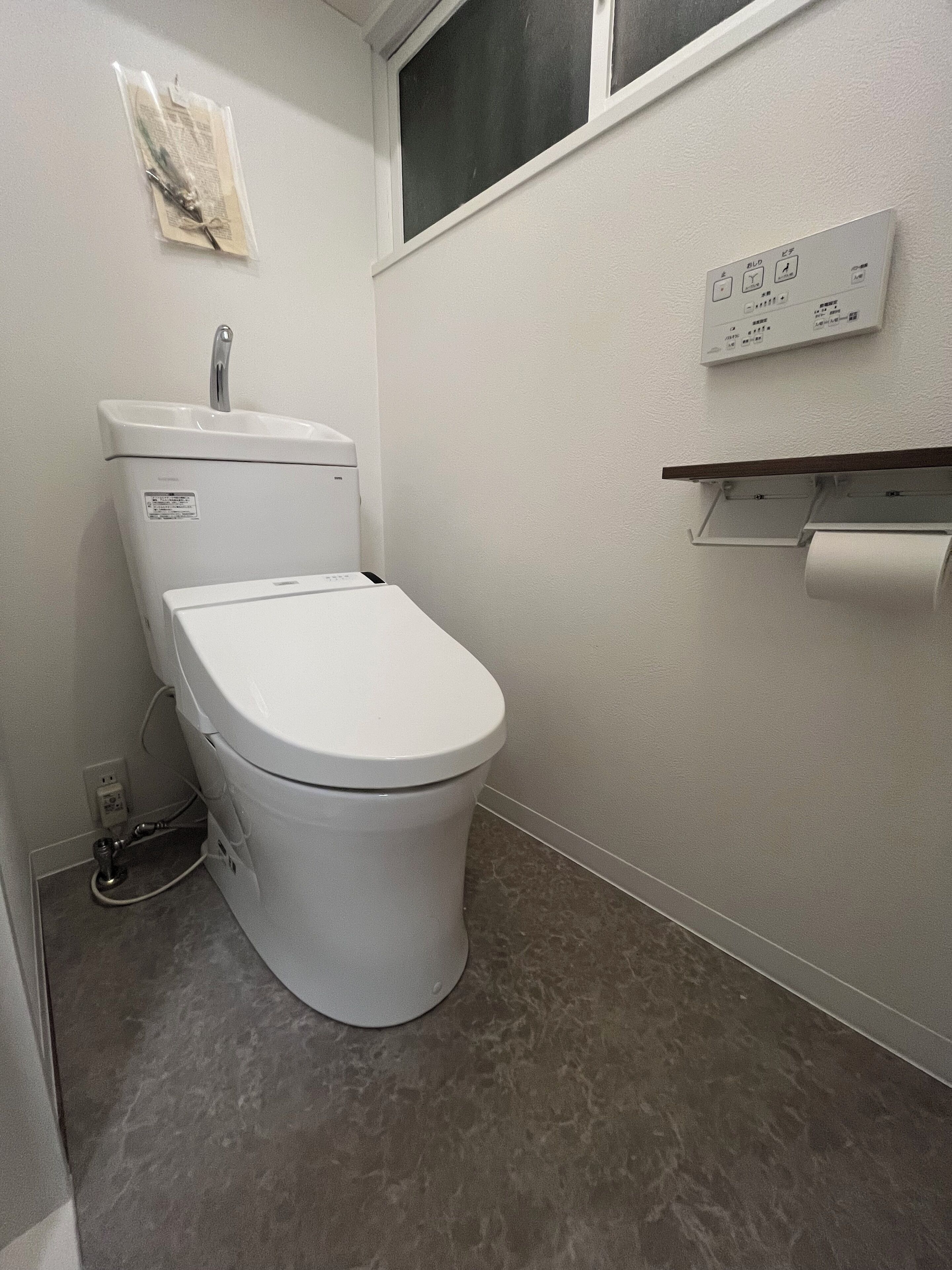 A small, modern bathroom with a white toilet, a wall-mounted sink, and a toilet paper holder.